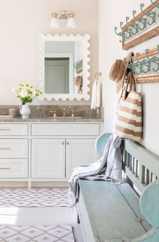 bathroom with pale blue vintage bench and coat pegs with sink in background and pattened rugs on floor