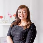 Head and shoulders shot of Gerry Rogers, founder of Petal's Edge Floral Design in front of a white backdrop with pink flowers in the background