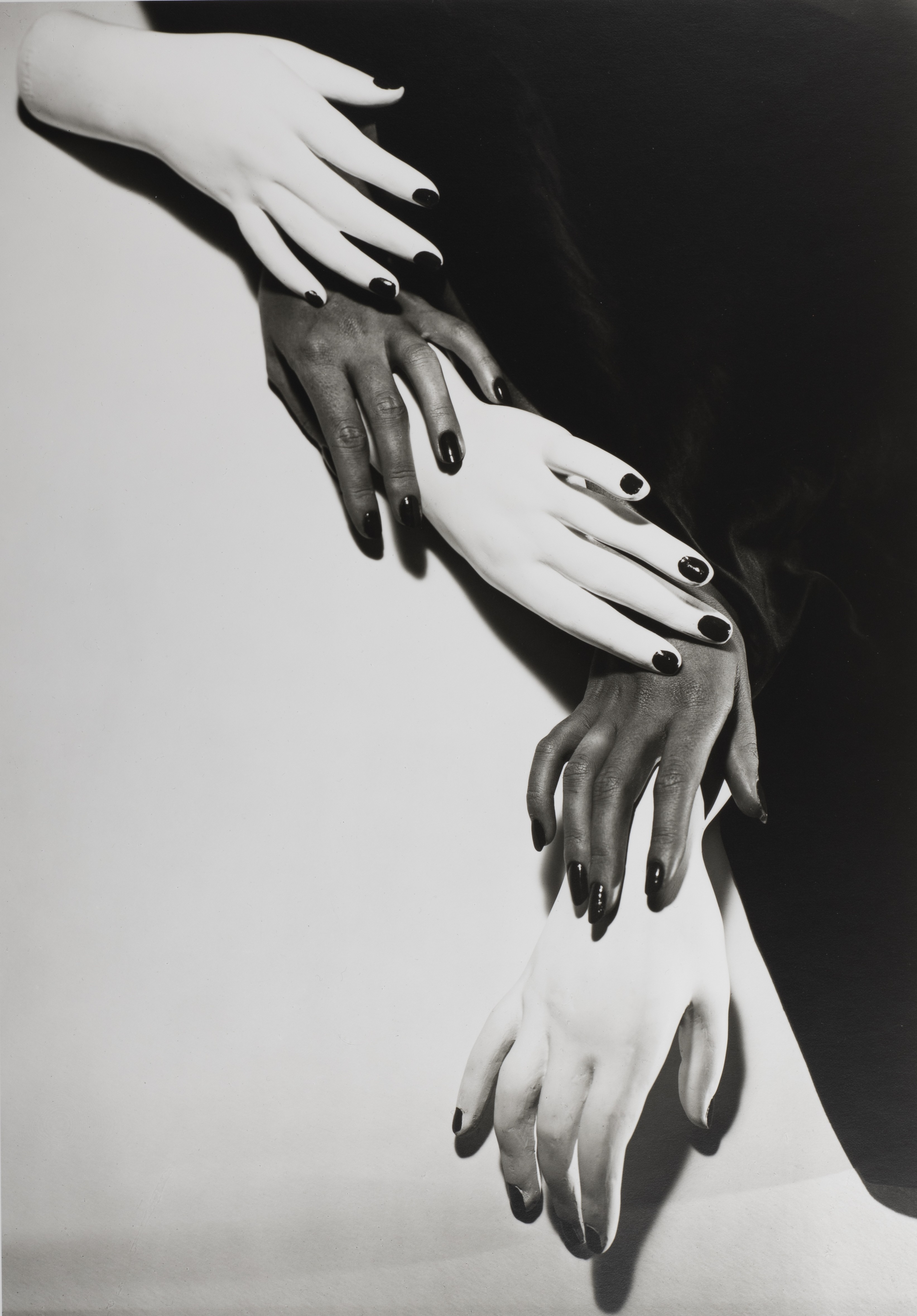 A high-contrast composition features a series of real and mannequin hands with dark nail polish intertwining across a split black-and-white background.