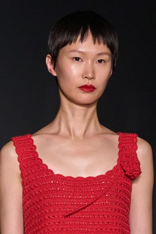 Model at Alejandra Alonso Rojas clp S25 show wearing red dress and red lipstick