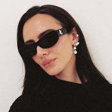A woman wearing black sunglasses and a black dress 