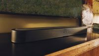 The Sonos Beam Ultra, photographed on a wooden sideboard beneath a TV