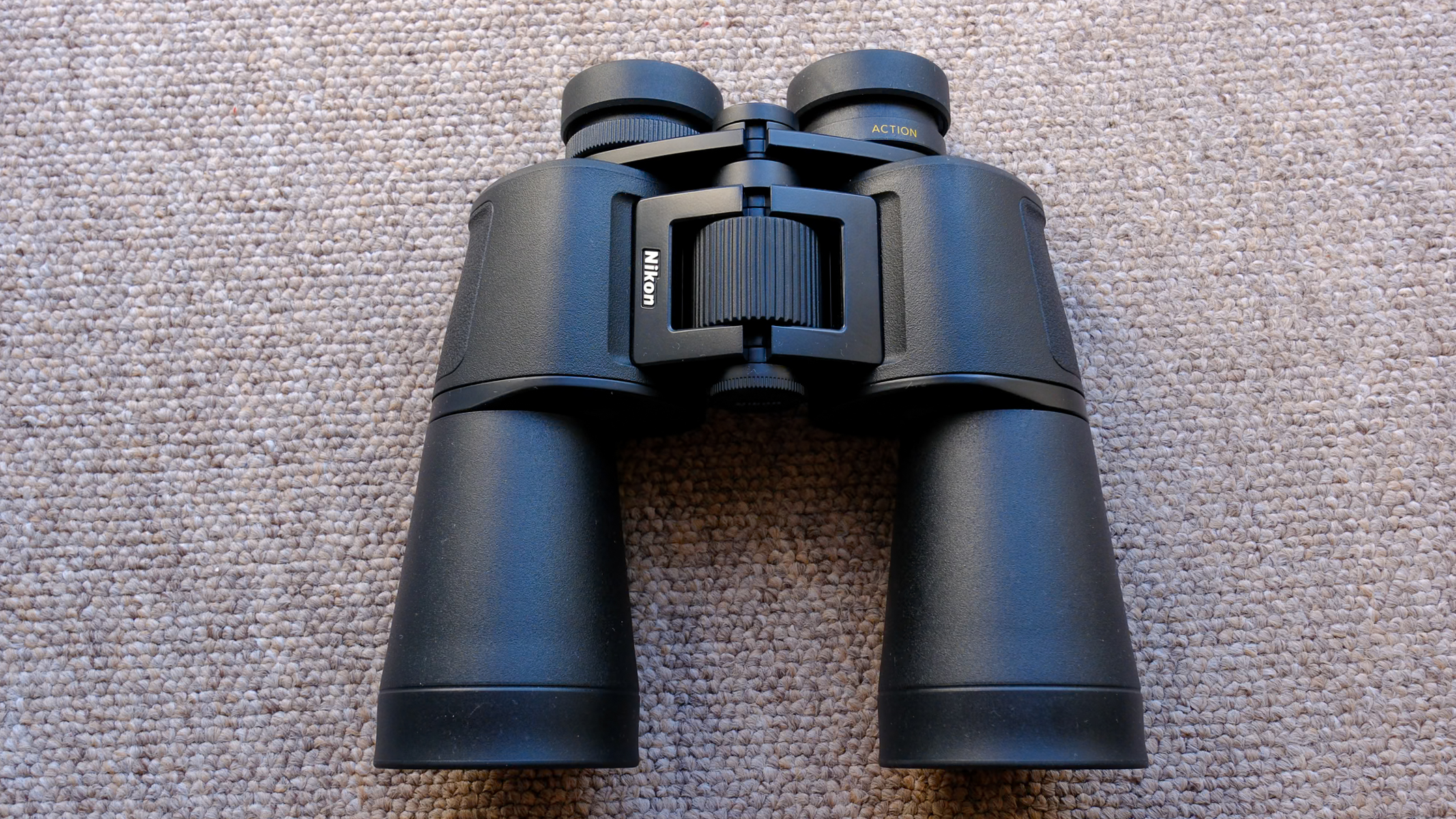 The Nikon Action 16x50 binoculars on a brown carpet.