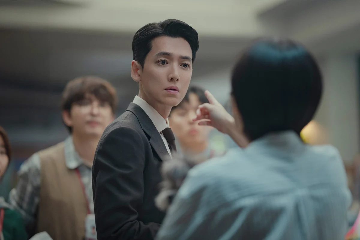 A woman with her back to the camera points a finger at a man (Jung Kyung-ho) as they stand in front of a crowd, in the K-drama &#039;Pro Bono.&#039;