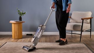 Tester using the Shark Freestyle Pro cordless upright vacuum on a carpet panel
