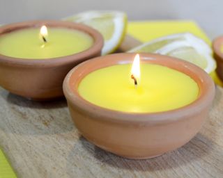 Yellow citronella candles, alight, with cut lemons in soft focus