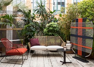 Black and red garden screening on decking area with painted wicker furniture