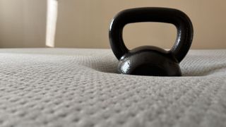 A kettlebell (weight unknown) sinking into the center of the Casper One Mattress to objectively test its level of pressure relief.