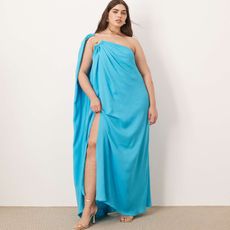 model wears aqua blue one-shoulder dress with silver shoes and earrings. 