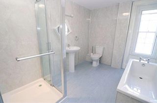 Before picture of bathroom with grey panel walls and grey-blue floor