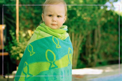Child wrapped in towel beside pool