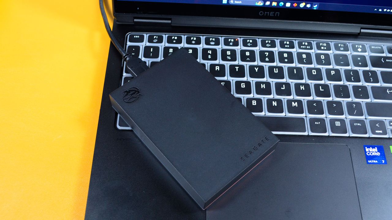 A Seagate FireCuda external gaming hard drive on a desk with a gaming laptop
