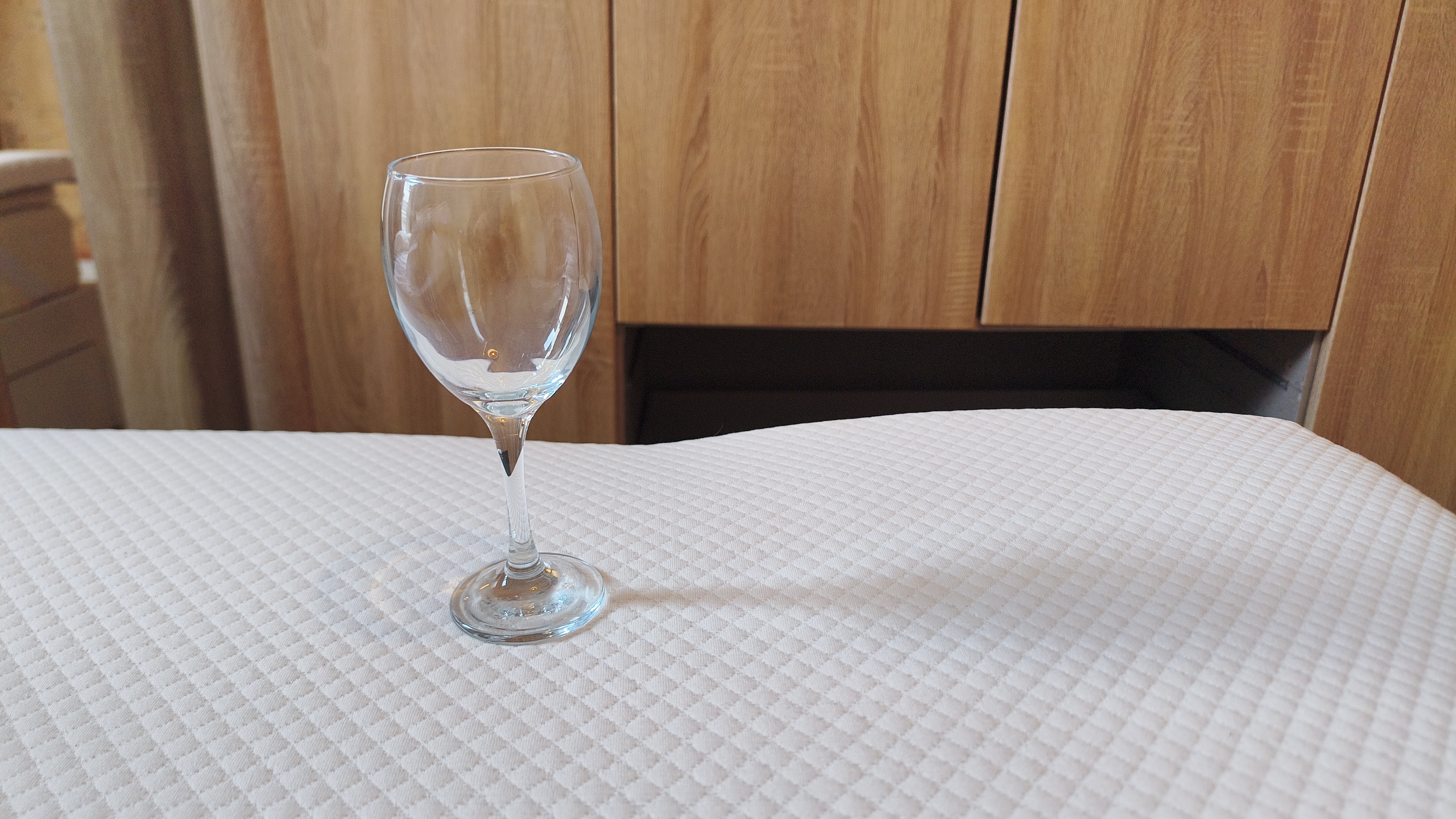 A wine glass standing upright on the surface of the Simba Cool Foam Mattress Topper to demonstrate its stability and motion-dampening properties.