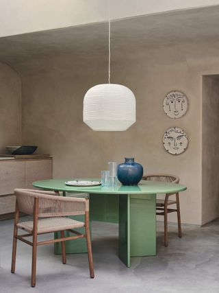 modern dining room with green circular table and large paper lantern pendant