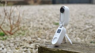 Insta360 Go 2 i sitt stativtillbehör på en träbänk