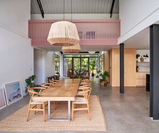 interior of barn with pink railed walkway spanning downstairs living area and joining upstairs rooms