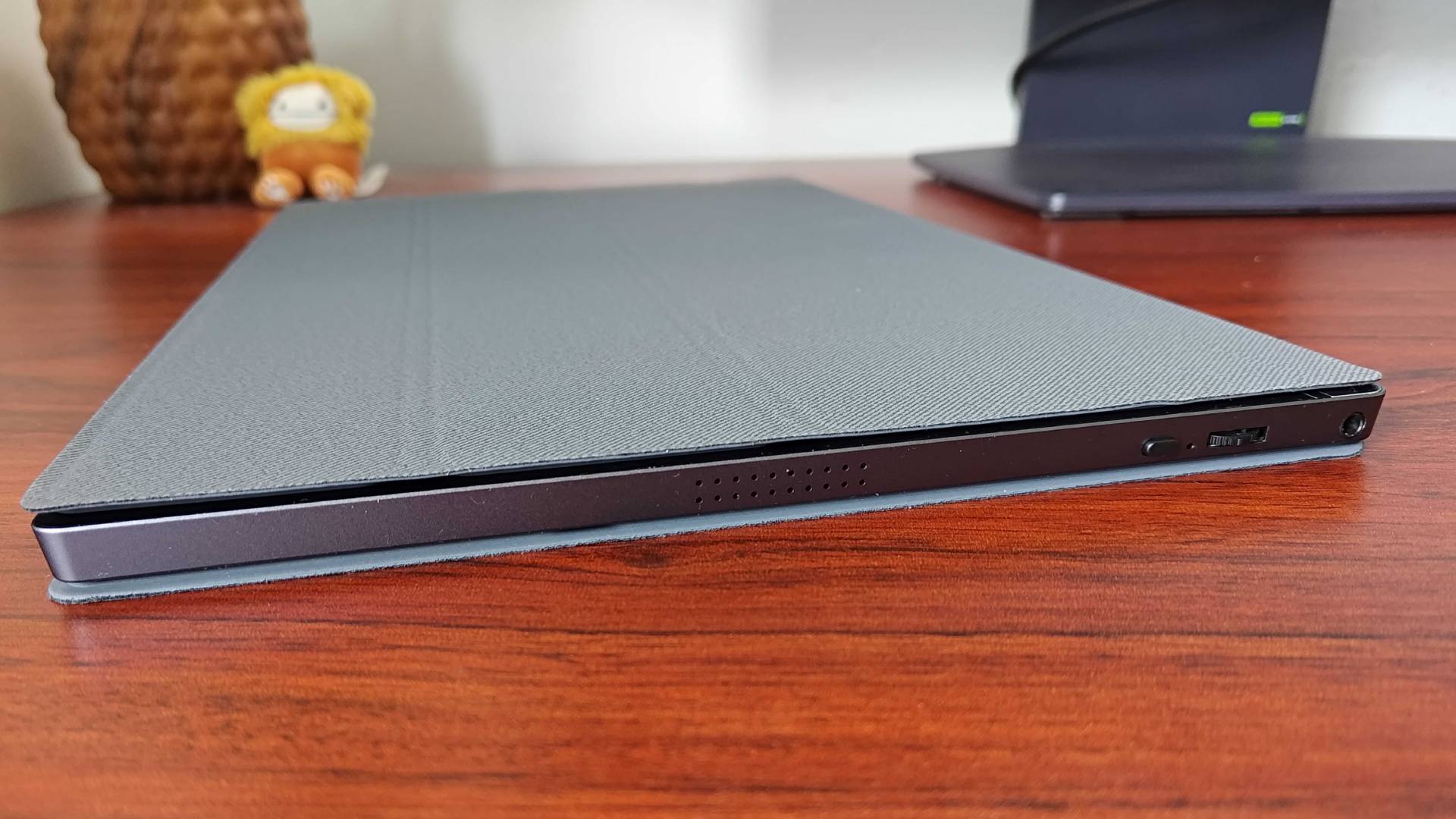 KYY K3 Portable monitor lying on woodgrain desk with cover closed.
