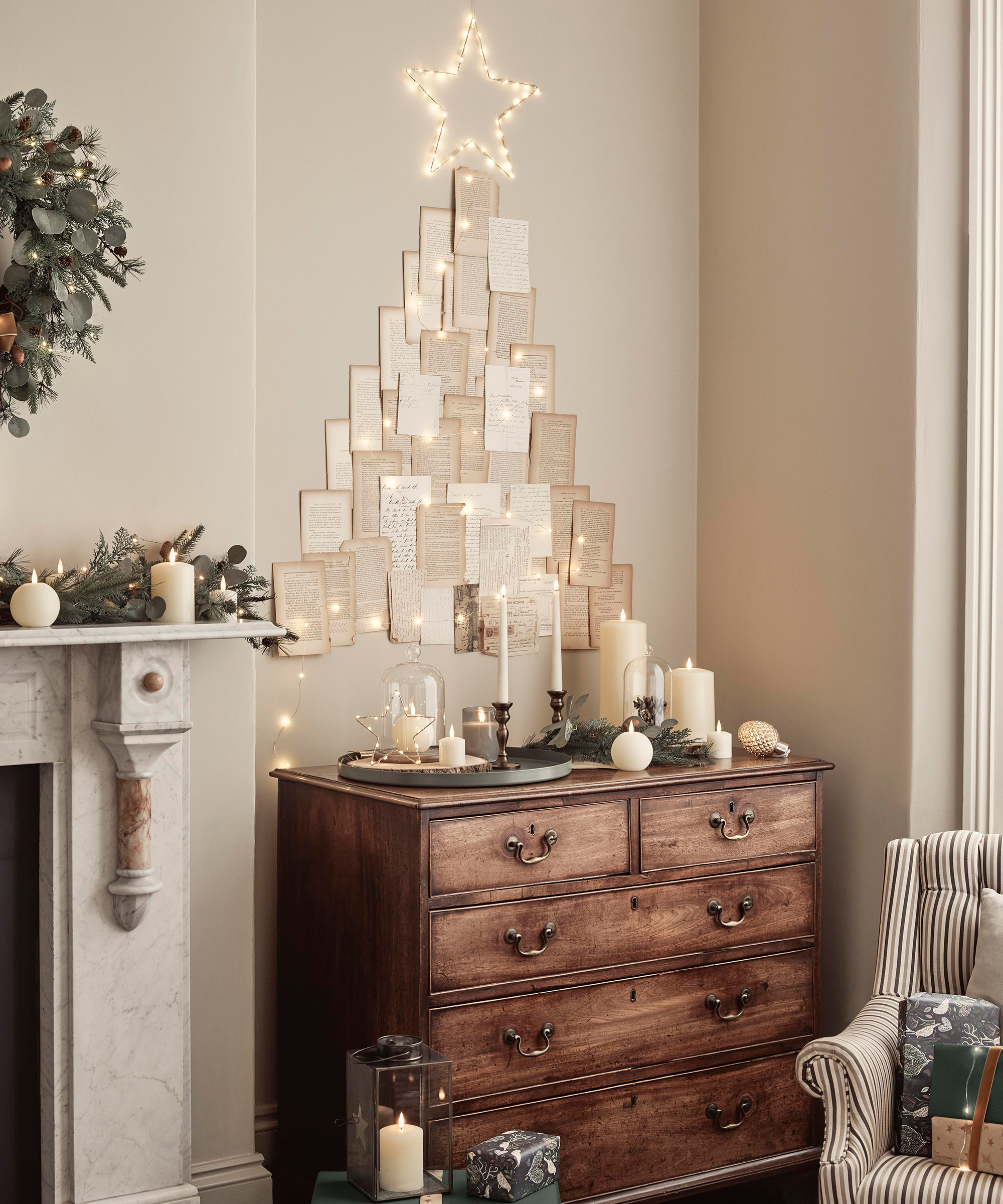 A cream Christmas living room with wooden chest of drawers and Christmas tree made from book pages and LED star