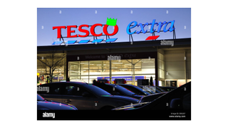 Photograph by Alamy of a Tesco Extra adorned with an LED green Christmas cracker hat.