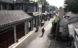 A man cycles down the road lined with courtyard houses