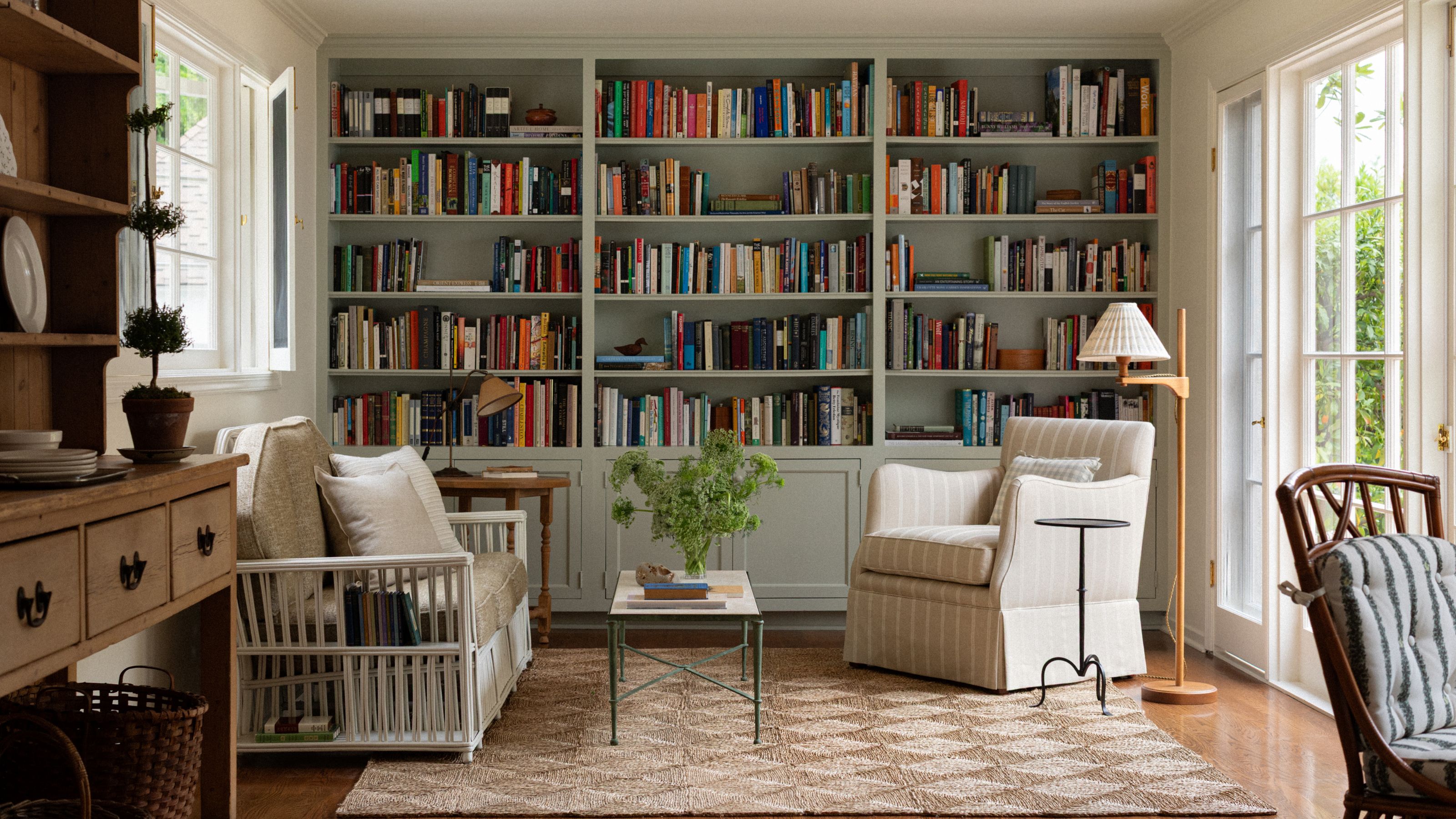 a sitting area and library at the end of a kitchen with french doors and a green bookcase