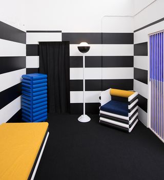 Conceptual hotel suite with black and white striped wall and colorful furniture