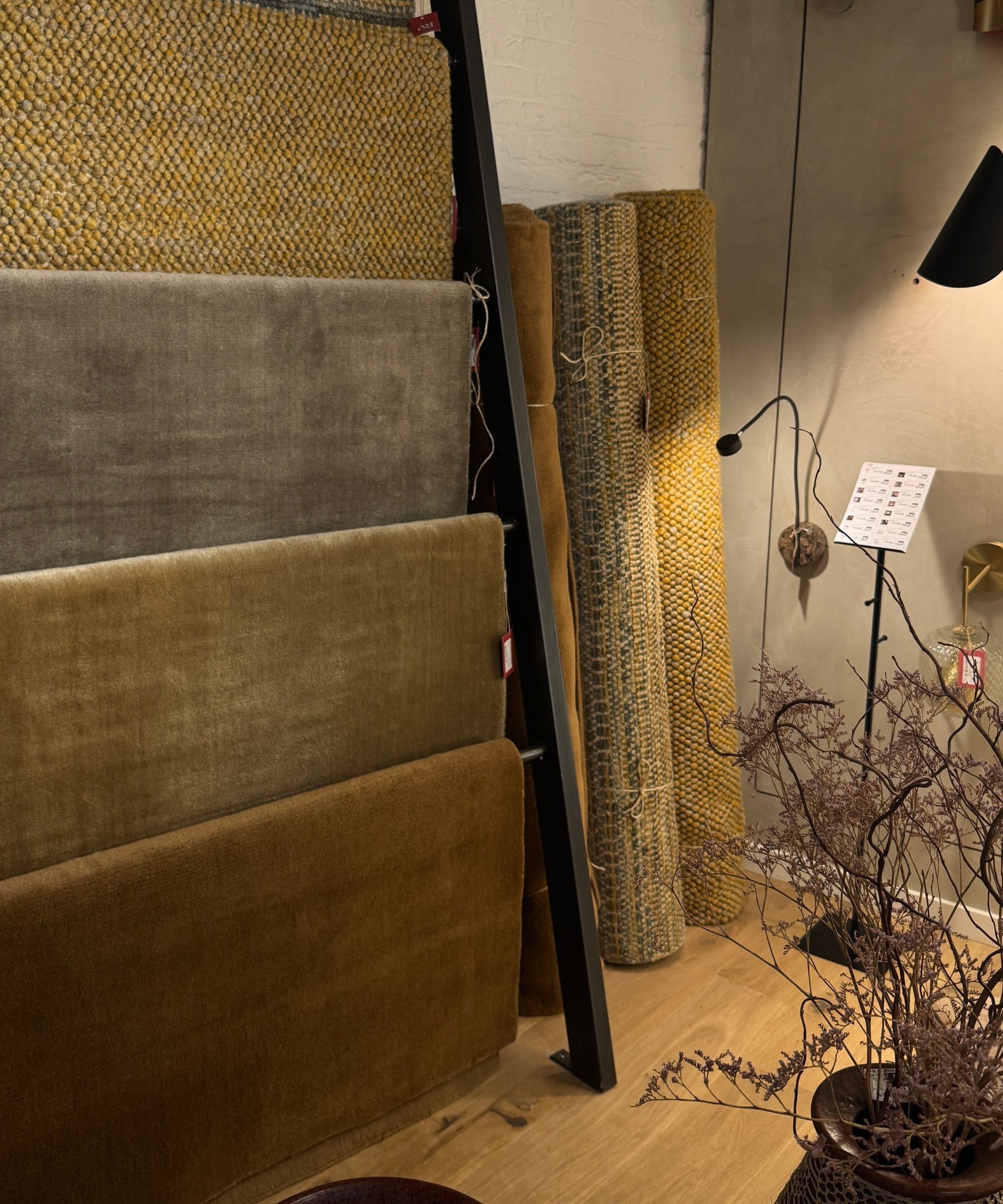 AM.PM Rugs hung on a rack and rolled leaning against the wall