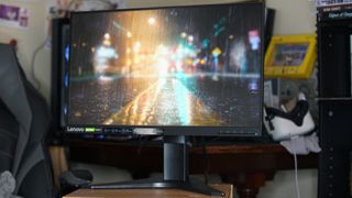 A Lenovo G25-10 gaming monitor showing a rainy street from a game