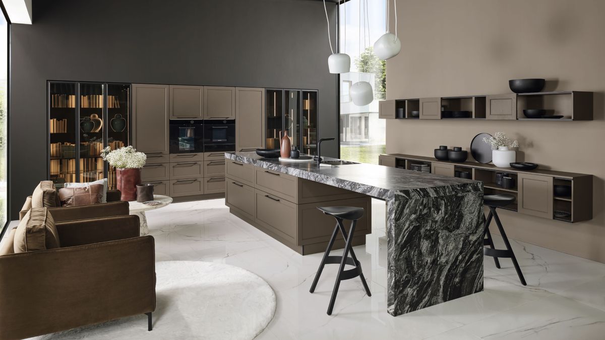 large open plan kitchen with central island, seating area and colour palette of brown, light stone and black and white veined marble