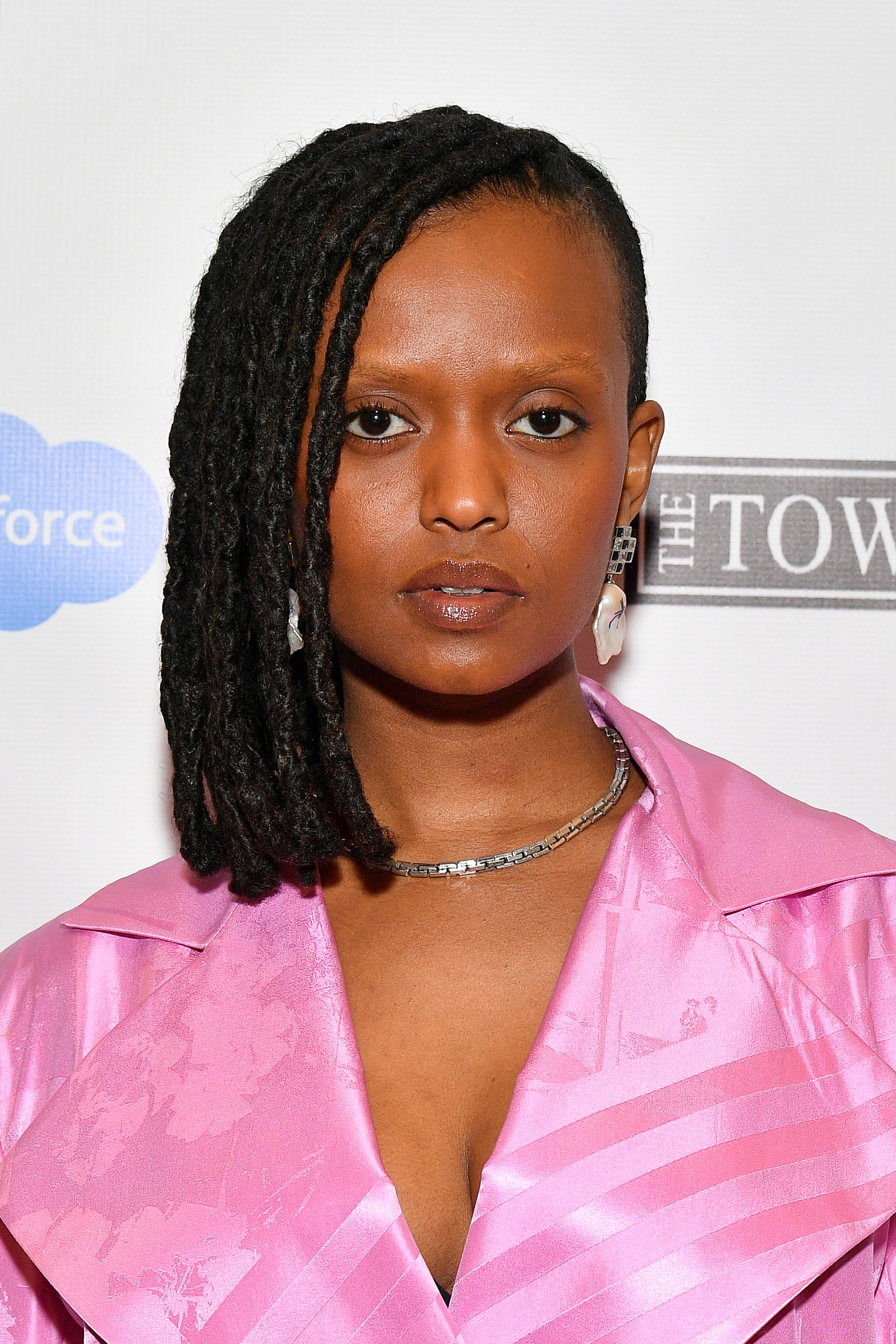 a black woman with short hair wearing a light pink blazer