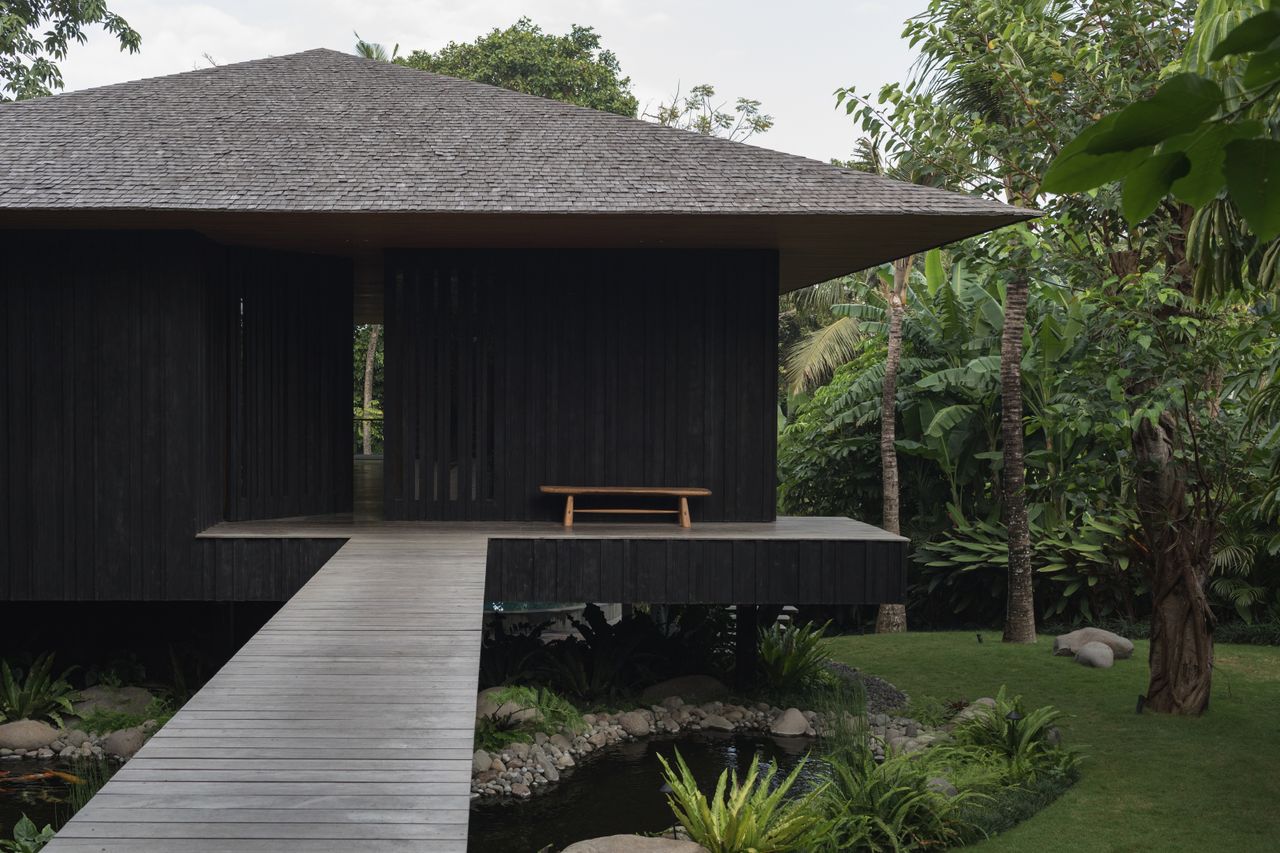 tsuki, a house in bali with pitched roof and natural materials set in lush tropical greenery