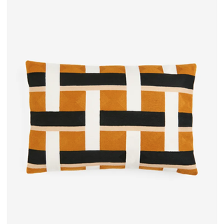 white, black and orange pillow in a woven block design