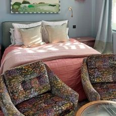 Stylist bedroom featuring the best luxury mattress, a pink duvet cover, and stylish printed ottomans.