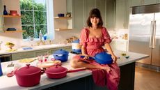 Selena Gomez sat on a kitchen countertop surrounded by blue and pink cookware and dinnerware