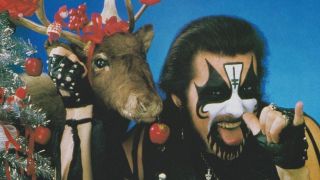 King Diamond posing next to a reindeer that has tinsel on its head