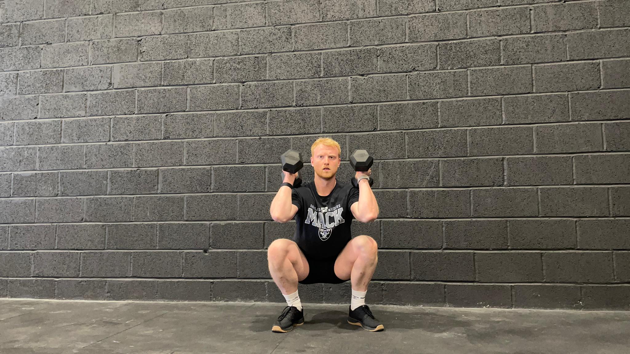 TechRadar fitness writer Harry Bullmore demonstrating a dumbbell thruster