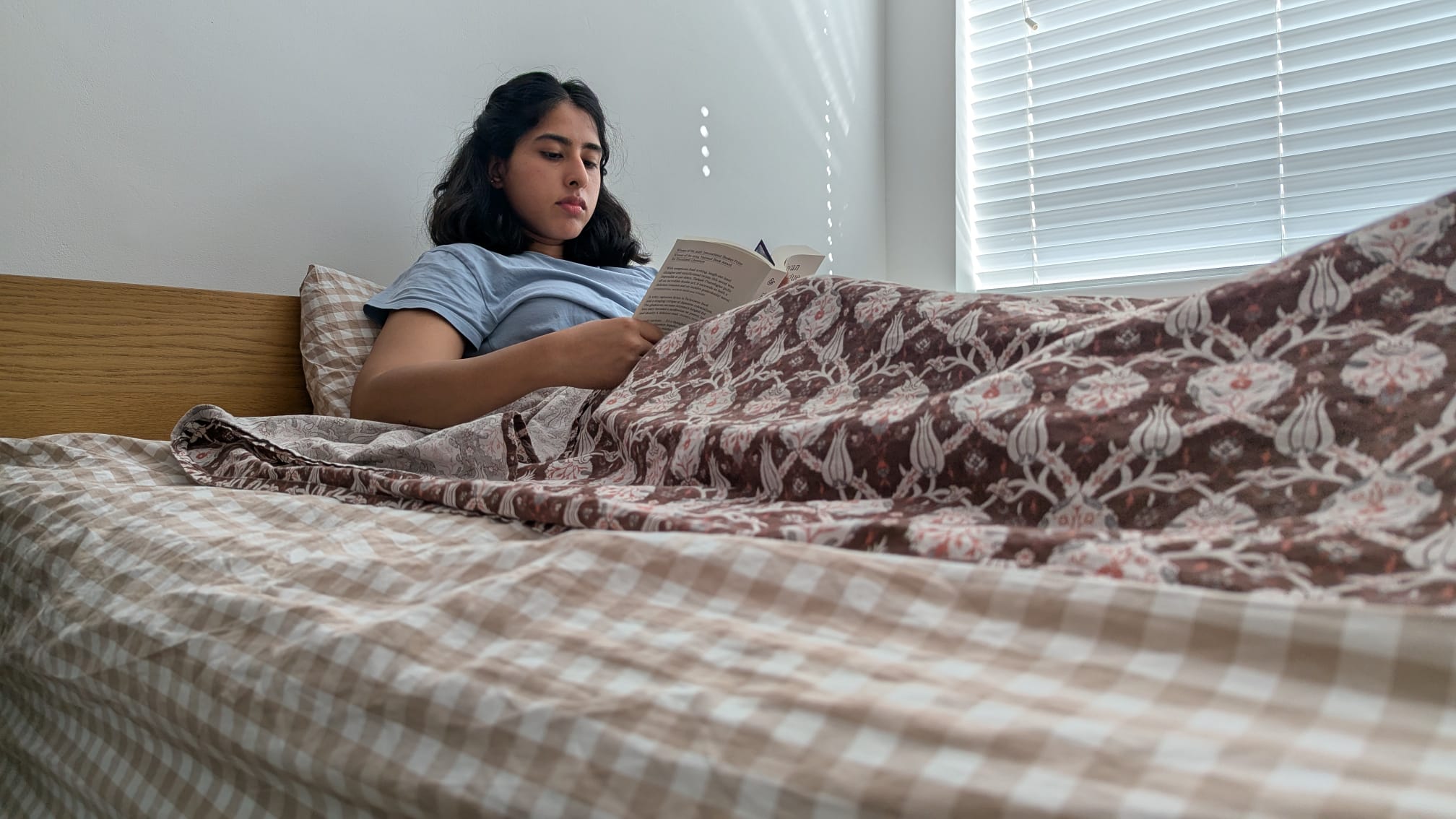Our tester sitting up on the Rejuvenate Personal Comfort mattress and reading in a brightly lit room