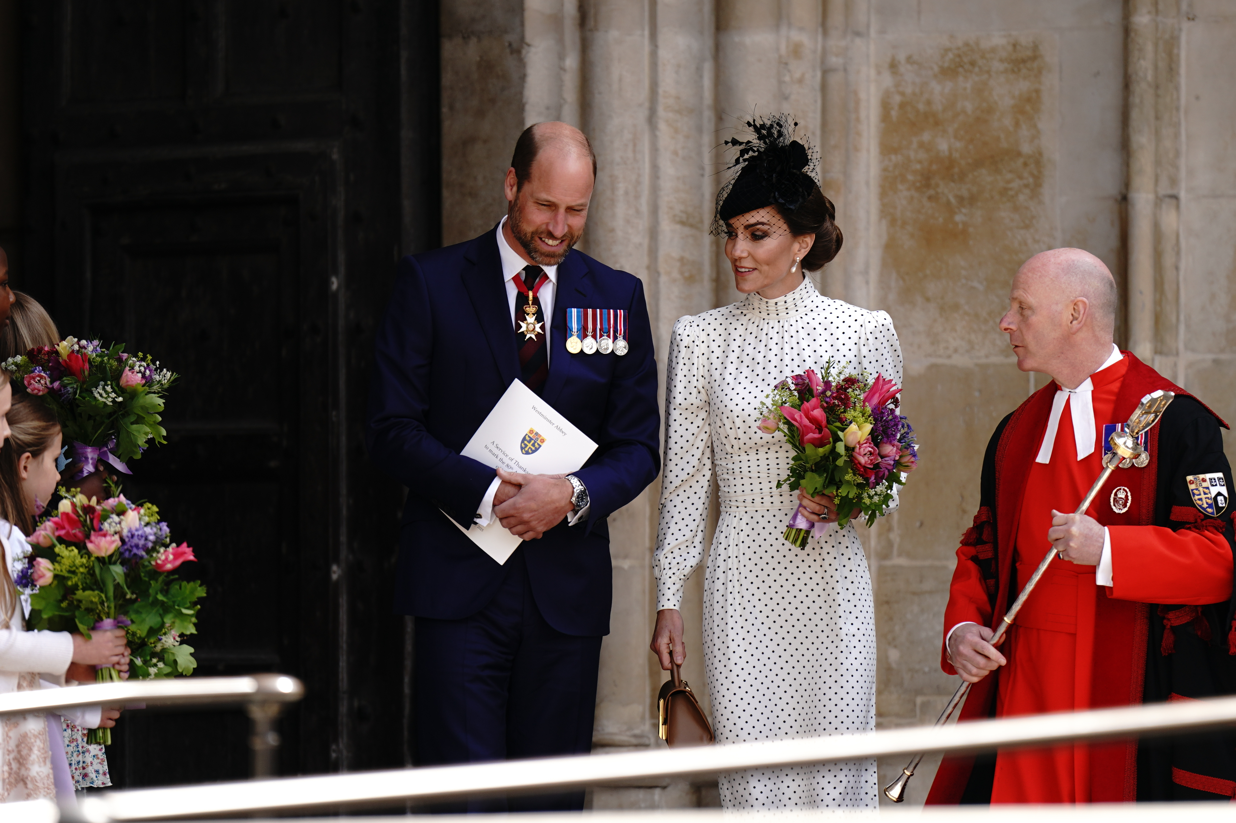 Kate Middleton and Prince William holding flowers at the VE Day ceremony on May 8