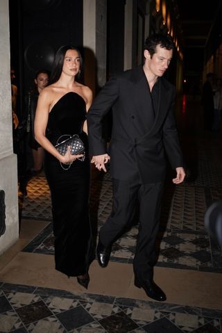 Dua Lipa and Callum Turner exude sophistication as they leave a restaurant hand-in-hand, heading to their hotel. Dua stuns in a strapless black velvet gown, while Callum complements her in a tailored double-breasted black suit, making a coordinated and stylish statement. on Jan. 28