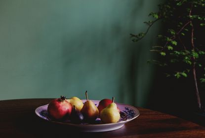 Fruit in a bowl on a table with a green background