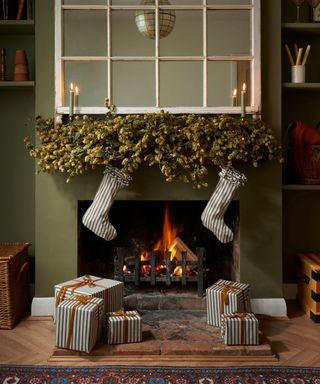 green living room with a fireplace with a foliage garland and stripe stockings and presents