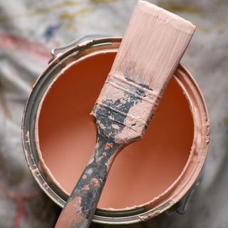 Open tin of peach paint with paint brush