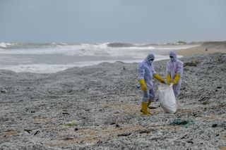 Sri Lankan Navy soldiers work to remove debris that washed ashore from a burning container ship.