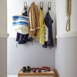 A light grey hallway with coats hanging on pegs