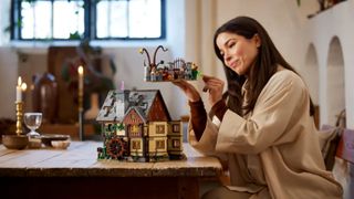 Lego Hocus Pocus set being held by a woman in a spooky, candle-lit room