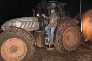 Jeremy Clarkson stepping down from a tractor at night