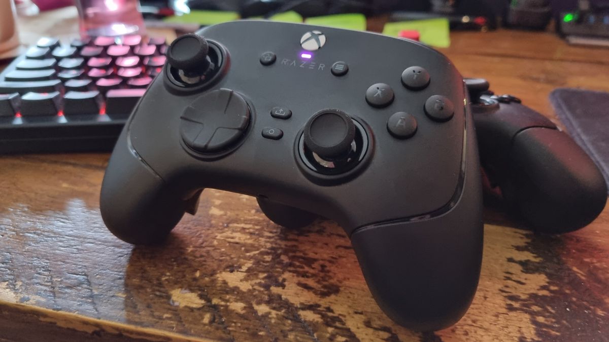 A Razer Wolverine V4 Pro stood up on a desk, in front of a controller and a gaming keyboard