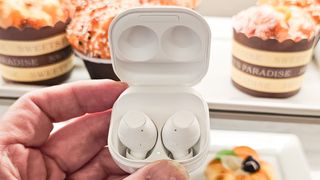 Someone holding the Samsung Galaxy Buds FE in white in their charging case.