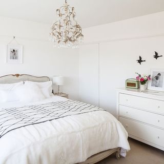 master bedroom with white walls and chandelier