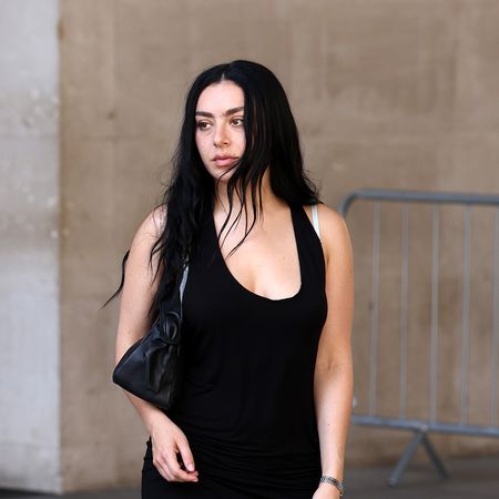 Charli xcx wearing a black mini dress, pink pumps, and a black bag